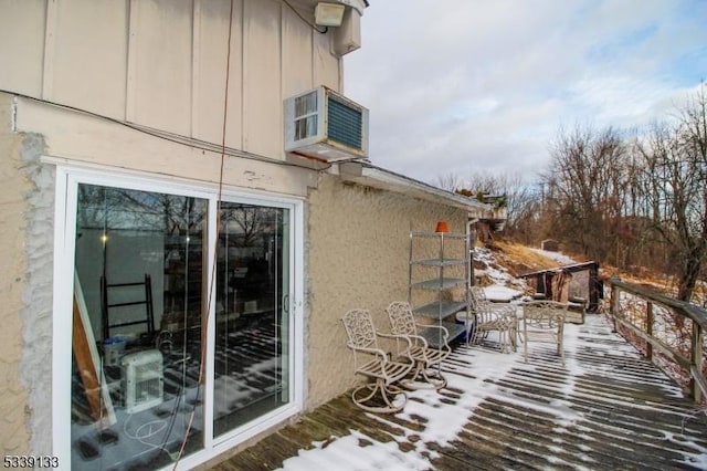 view of snowy exterior with board and batten siding and a wooden deck