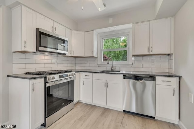 166 E Camplain Rd, Manville Boro, NJ 08835 - kitchen with appliances with stainless steel finishes, a sink, dark countertops, white cabinets, and light wood-style floors