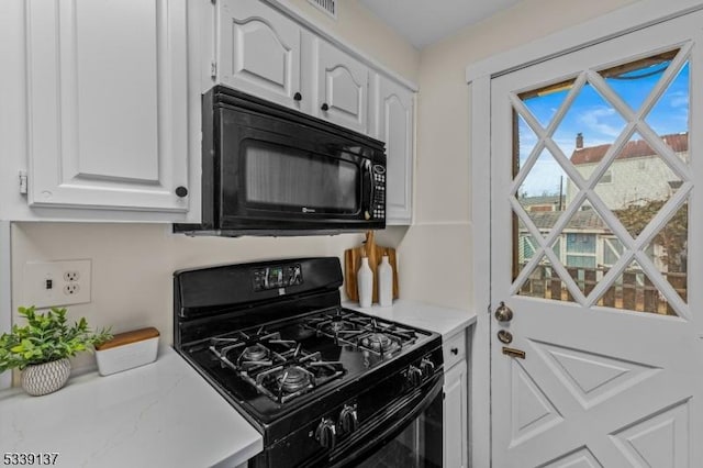 kitchen featuring light countertops, white cabinets, and black appliances