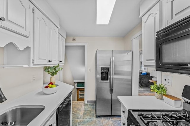 kitchen with a sink, black appliances, light countertops, and white cabinetry