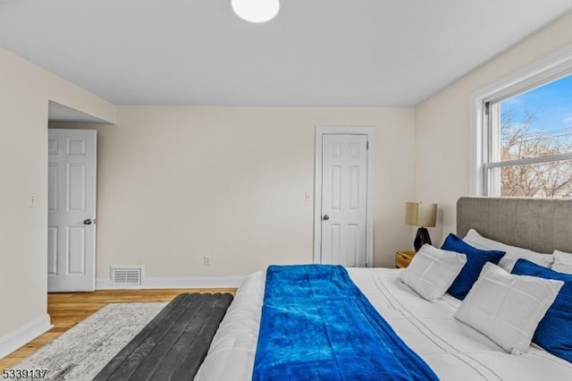 bedroom with baseboards, visible vents, and light wood finished floors