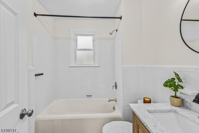 bathroom featuring shower / washtub combination, a wainscoted wall, tile walls, toilet, and vanity