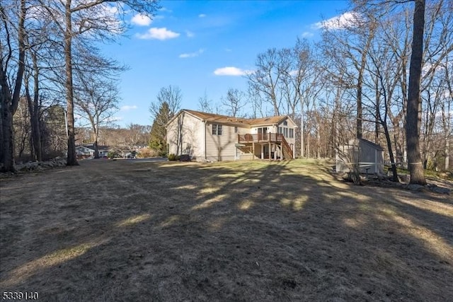 rear view of property featuring a yard, an outdoor structure, stairs, and a deck