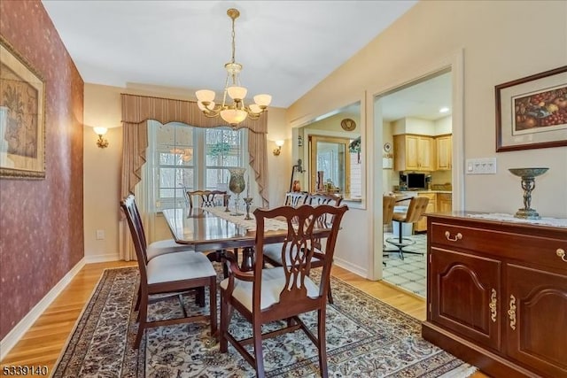 dining area with light wood-style flooring, an inviting chandelier, and baseboards