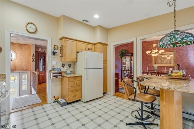 kitchen with visible vents, pendant lighting, light brown cabinetry, freestanding refrigerator, and light floors