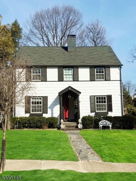 colonial-style house with a chimney and a front lawn