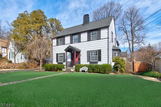 colonial-style house with a chimney and a front lawn