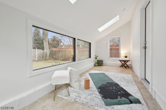 living area with lofted ceiling with skylight, baseboards, and a wealth of natural light