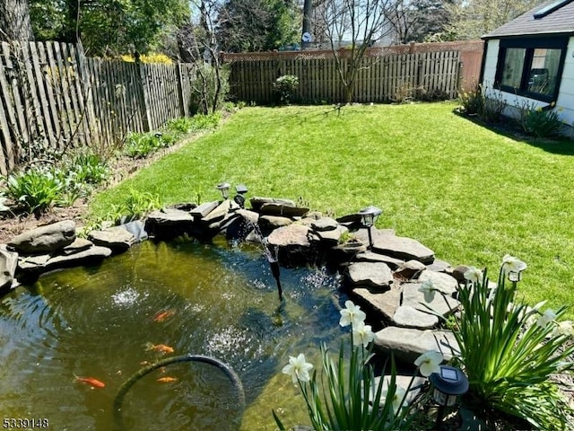 view of yard with a garden pond and a fenced backyard