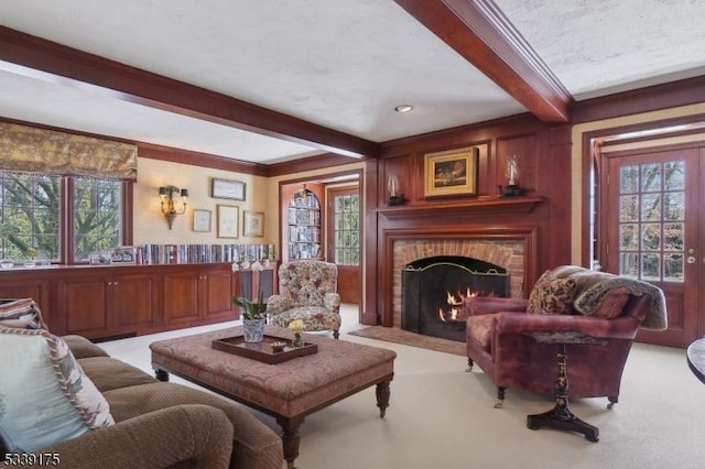 living room with light carpet, a wealth of natural light, a fireplace, and beamed ceiling