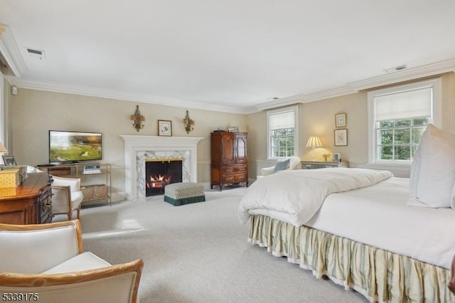 carpeted bedroom featuring visible vents, crown molding, and a premium fireplace