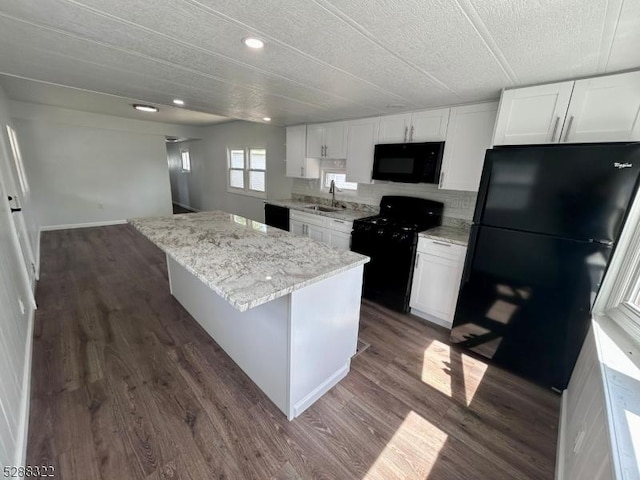 kitchen with dark hardwood / wood-style flooring, a kitchen island, black appliances, sink, and white cabinets