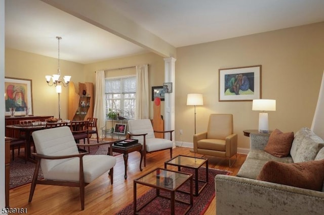 living room featuring beam ceiling, a chandelier, decorative columns, and hardwood / wood-style floors