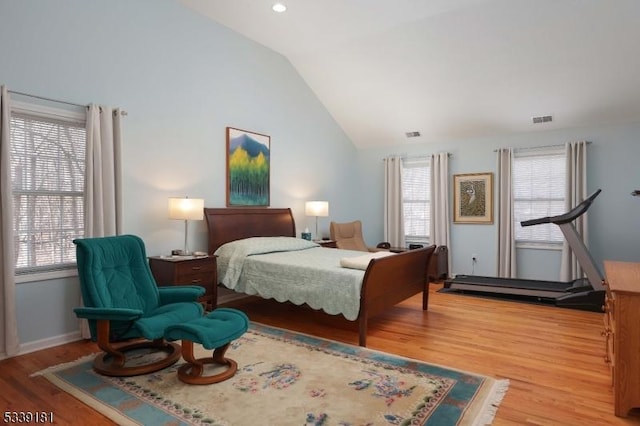 bedroom with vaulted ceiling, multiple windows, and wood-type flooring