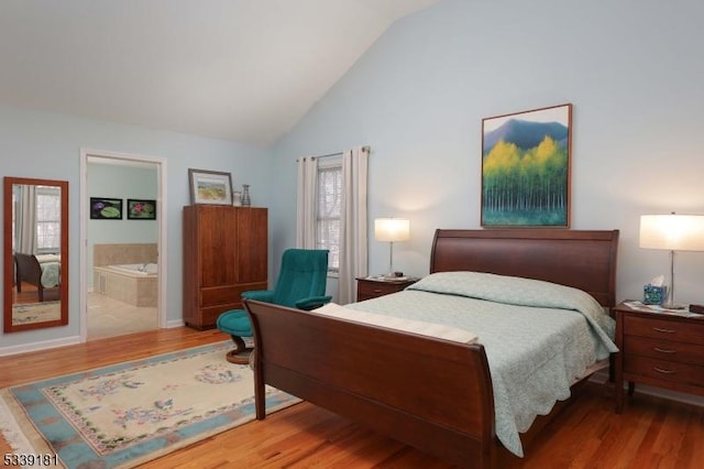 bedroom with vaulted ceiling, ensuite bath, and wood-type flooring