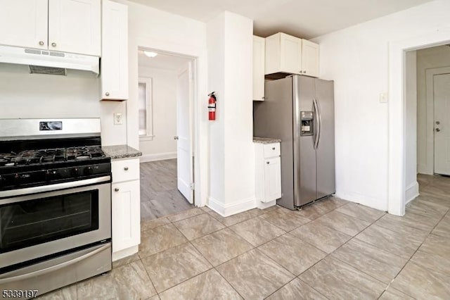 kitchen featuring under cabinet range hood, stainless steel appliances, white cabinetry, baseboards, and dark stone counters