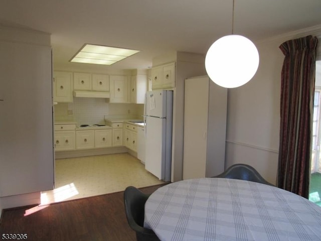 kitchen featuring decorative backsplash, white appliances, white cabinetry, and pendant lighting