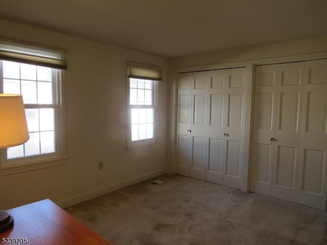 unfurnished bedroom featuring two closets and light colored carpet