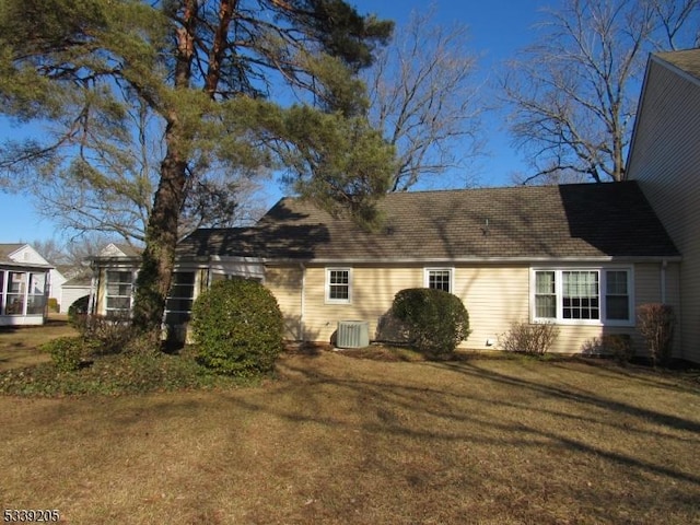 view of side of home featuring central AC unit and a lawn