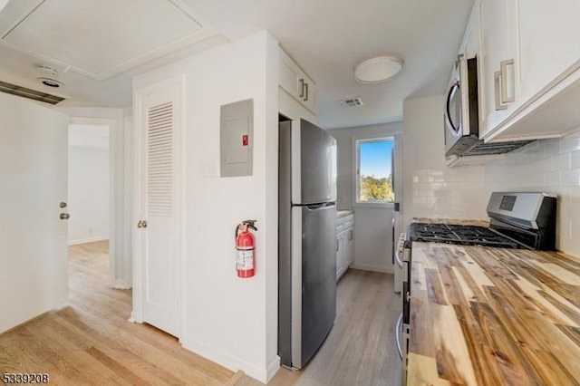 kitchen with white cabinets, electric panel, stainless steel appliances, and butcher block counters