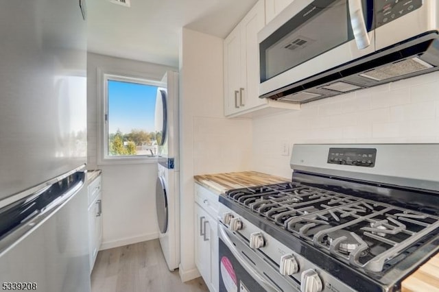 kitchen featuring white cabinetry, light hardwood / wood-style flooring, backsplash, appliances with stainless steel finishes, and wooden counters