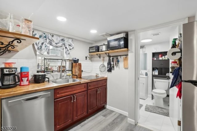 kitchen with decorative backsplash, dishwasher, butcher block counters, and sink