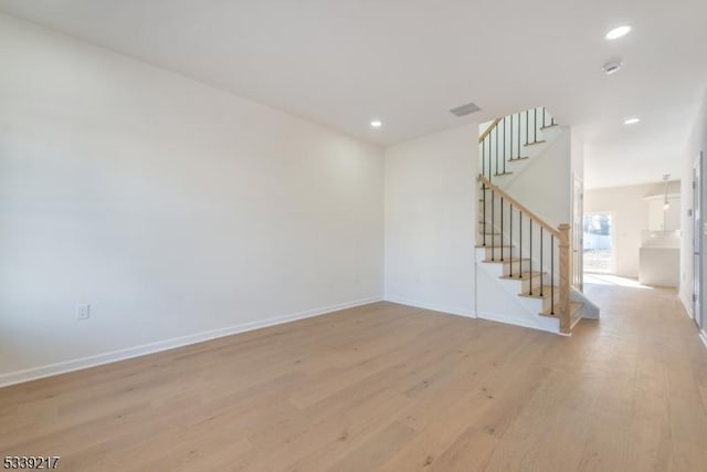 spare room featuring light wood finished floors, stairway, recessed lighting, and baseboards