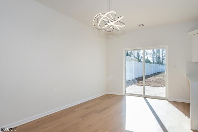 unfurnished dining area featuring baseboards, an inviting chandelier, visible vents, and light wood-style floors