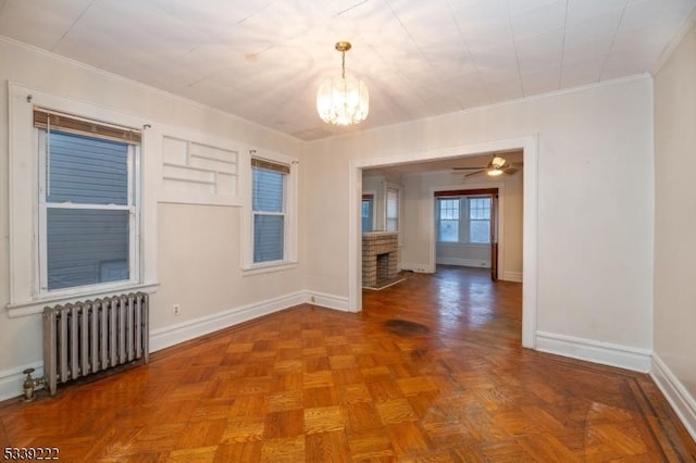 empty room with parquet floors, crown molding, radiator, and a fireplace