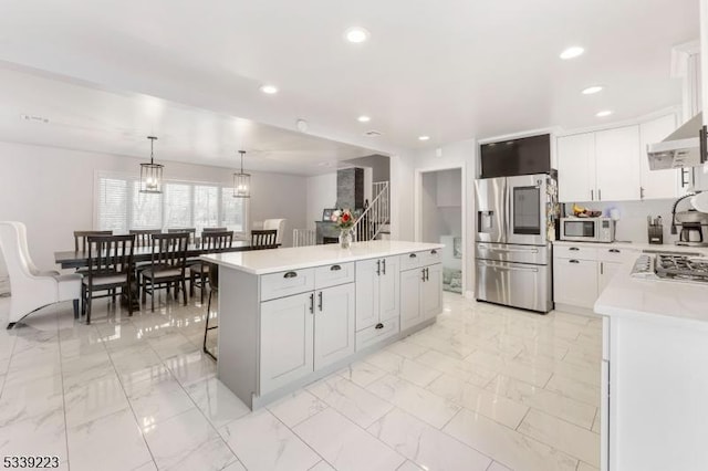 kitchen with white cabinets, appliances with stainless steel finishes, light countertops, and a center island