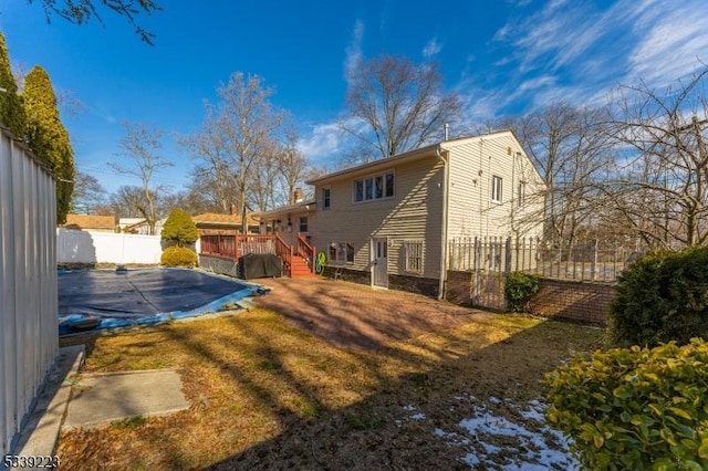 rear view of property with a fenced backyard, a lawn, a deck, and a fenced in pool