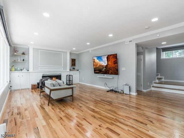 sitting room featuring a fireplace, crown molding, and light wood-type flooring