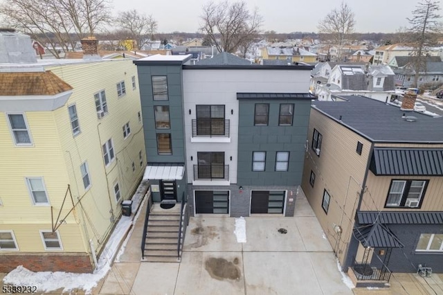 view of building exterior featuring a residential view, driveway, stairway, and a garage