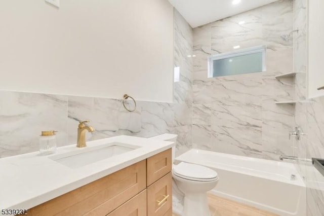 bathroom with vanity, tile walls, toilet, and tub / shower combination