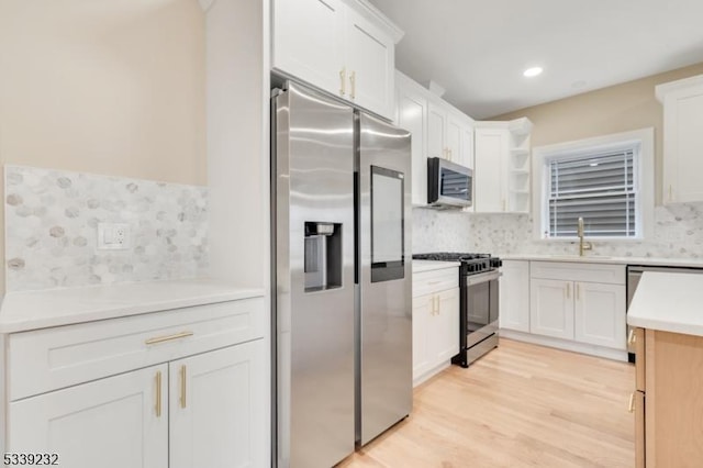 kitchen featuring a sink, open shelves, white cabinetry, stainless steel appliances, and light wood finished floors