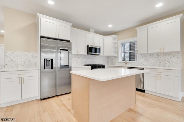 kitchen featuring light wood-style flooring, appliances with stainless steel finishes, a kitchen island, and white cabinetry