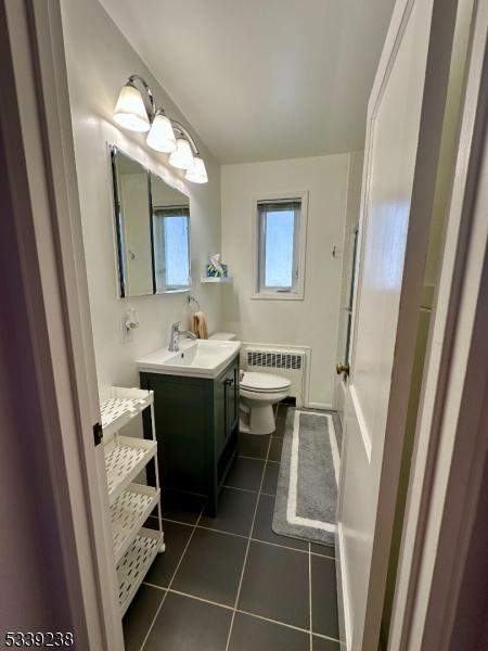 bathroom featuring vanity, tile patterned flooring, radiator, and toilet