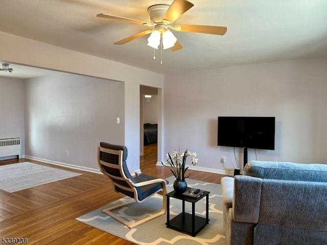 living room featuring hardwood / wood-style flooring, ceiling fan, and radiator