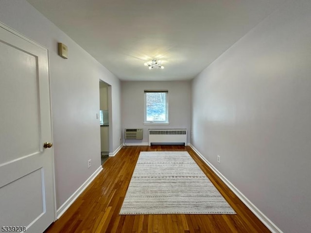 interior space with dark wood-type flooring, an AC wall unit, and radiator heating unit