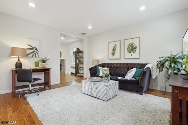 living room with visible vents, baseboards, wood finished floors, a fireplace, and recessed lighting