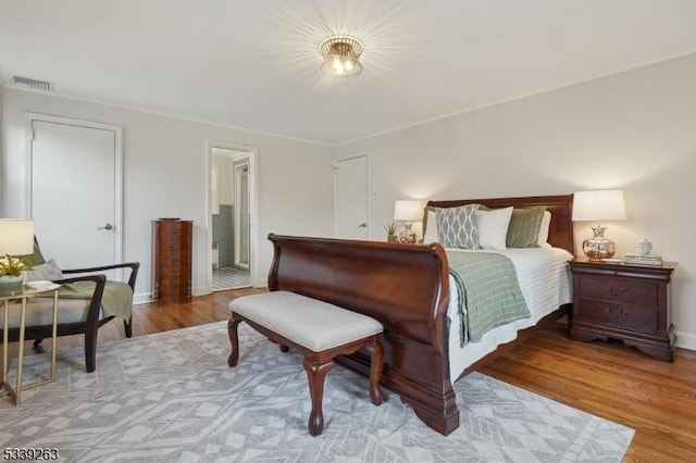 bedroom featuring light wood-style floors, visible vents, and ensuite bath