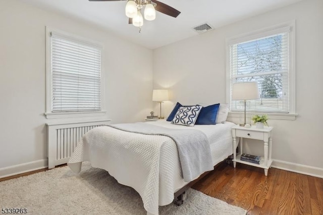 bedroom featuring radiator, baseboards, visible vents, and wood finished floors