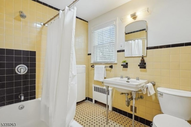 bathroom featuring radiator, shower / tub combo, toilet, and tile walls