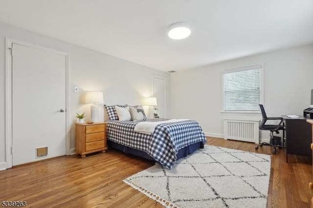 bedroom with radiator heating unit and wood finished floors