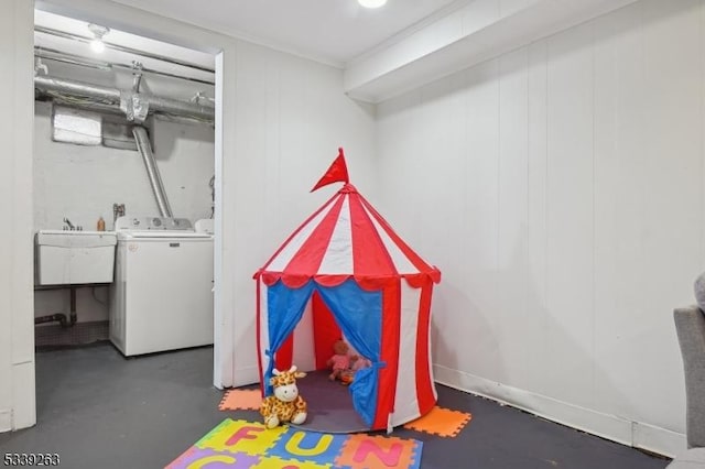 playroom featuring a sink, washing machine and clothes dryer, and finished concrete floors