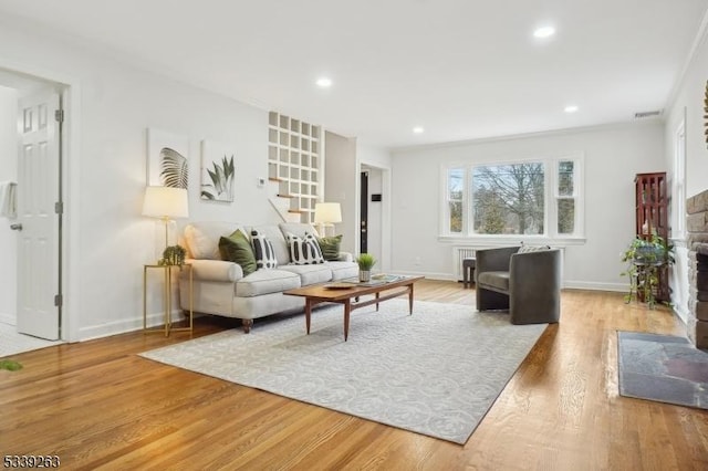 living room with visible vents, stairway, a fireplace with flush hearth, light wood-style floors, and baseboards