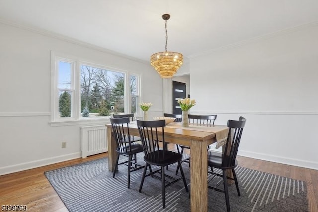 dining space with baseboards, ornamental molding, wood finished floors, and radiator