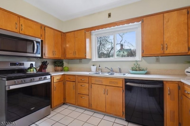 kitchen with a sink, stainless steel appliances, brown cabinetry, and light countertops