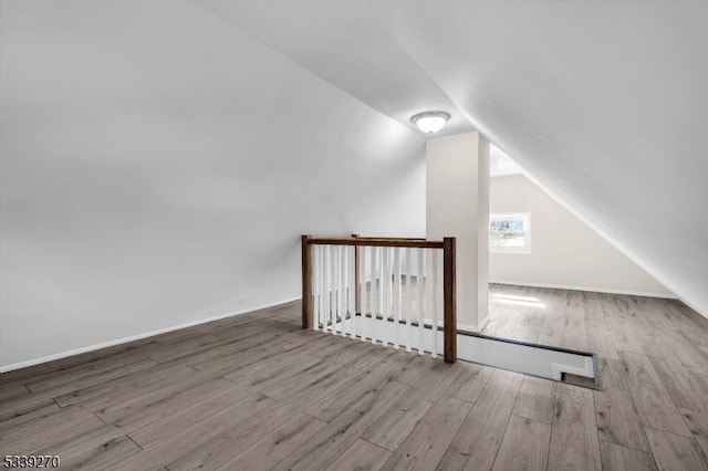 bonus room with lofted ceiling and light wood-type flooring