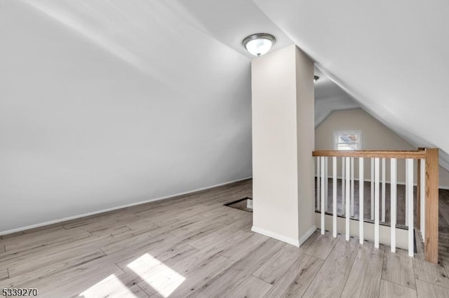 bonus room with lofted ceiling, light wood-type flooring, and baseboards